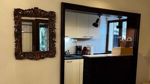 Une cuisine avec des armoires blanches, un plan de travail en pierre et un tabouret en bois.