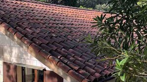 Un bâtiment avec un toit recouvert de tuiles rouges et une fenêtre dotée d’un cadre en bois.