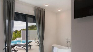 A modern bathroom with a bathtub, a shower, and a glass door leading to a pool area. - Villa Antonio - Four bedroom Villa with swimming pool (Island of Solta)