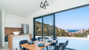 A modern kitchen with white cabinets, a wooden countertop, and a large window overlooking a scenic view. - Villa Antonio - Four bedroom Villa with swimming pool (Island of Solta)