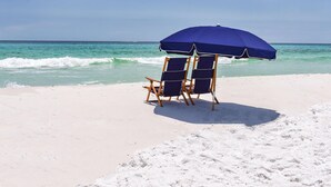 Une plage avec deux chaises longues bleues et un parasol assorti.