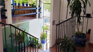 Un escalier menant à un balcon agrémenté de plantes en pot et offrant une vue sur un jardin.