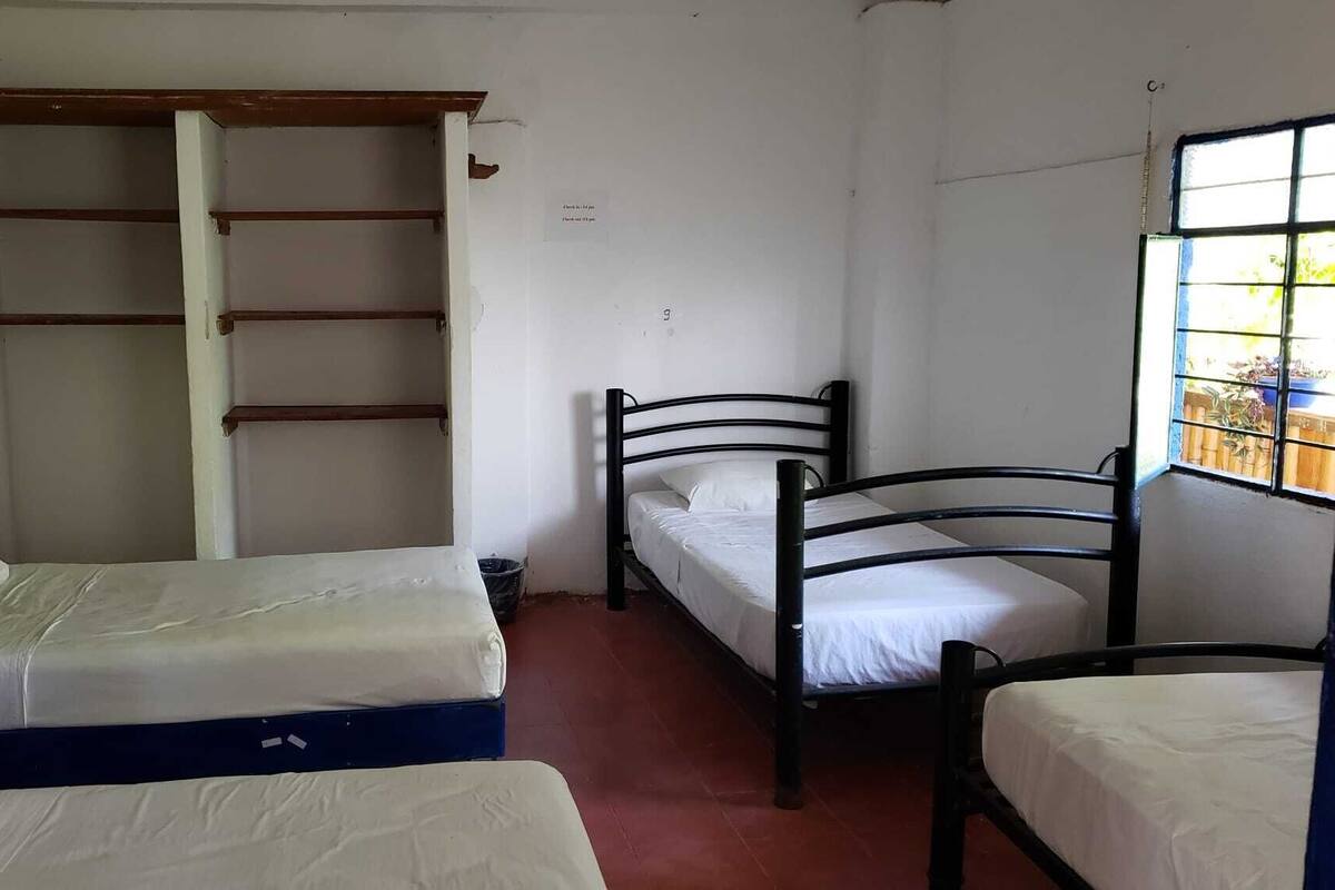 Ein Schlafsaalzimmer mit zwei Einzelbetten, einem Kleiderschrank und einem Fenster mit Blick ins Freie.