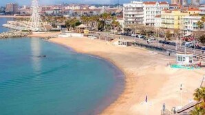 A coastal cityscape with a sandy beach, a prominent tower, and historic buildings. - Little John Mobil Home (Fréjus)