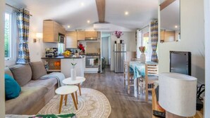 A modern kitchen with a central island, a dining area with a table and chairs, and a living room with a sofa and a coffee table. - Little John Mobil Home (Fréjus)