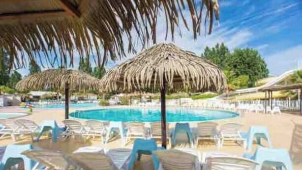A pool area with lounge chairs and thatched umbrellas. - Little John Mobil Home (Fréjus)