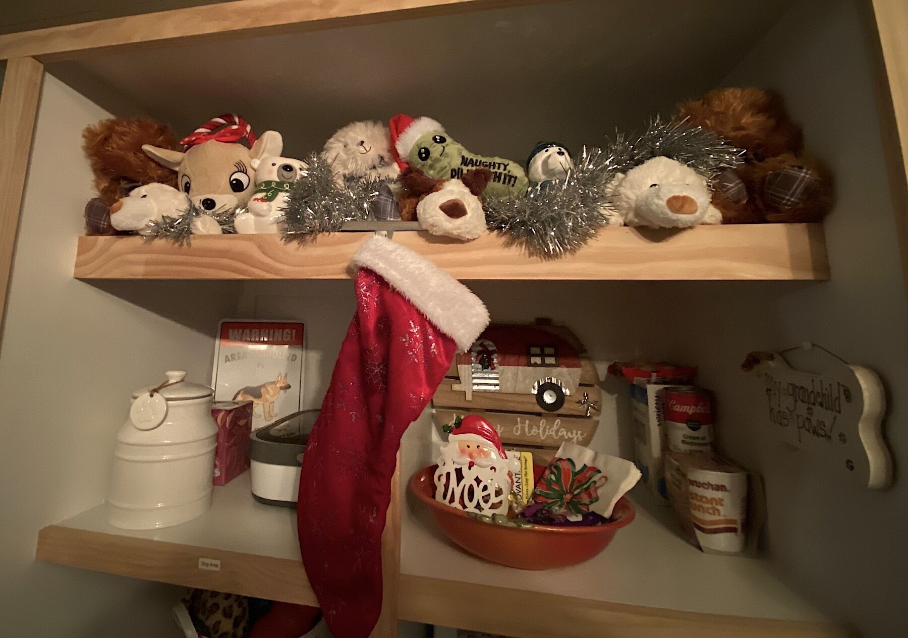 A shelf with various Christmas decorations including stuffed animals, a Christmas stocking, and a small toy train.