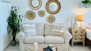 A living room with a beige sofa, a wooden coffee table, and a hanging woven light fixture. - 5 minutes to SJU airport, Steps to Isla Verde Beach, 16th Fl. w/Prkg @ESJ Towers (Carolina)