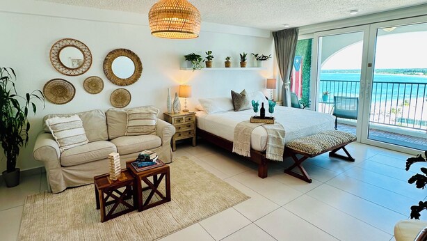 A spacious living room with a sofa, coffee table, and a bed with a view of the sea. - 5 minutes to SJU airport, Steps to Isla Verde Beach, 16th Fl. w/Prkg @ESJ Towers (Carolina)
