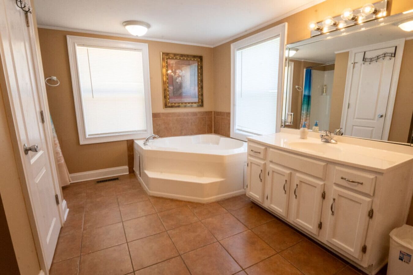 A bathroom with a bathtub, vanity with cabinets, and a large mirror.