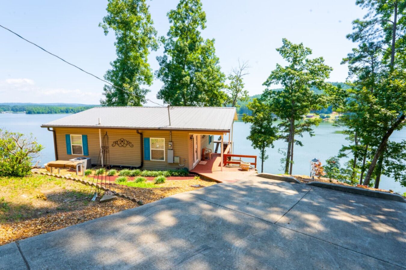 Una piccola cabina con un portico, una zona salotto esterna coperta e vista su un lago.