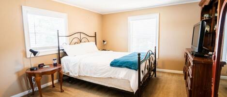 Une chambre à coucher avec un lit simple, une table de chevet, une commode et un téléviseur.