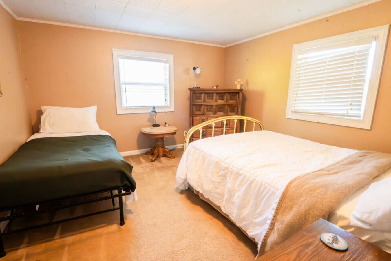 A room with two beds, a small round table, and a wooden cabinet.