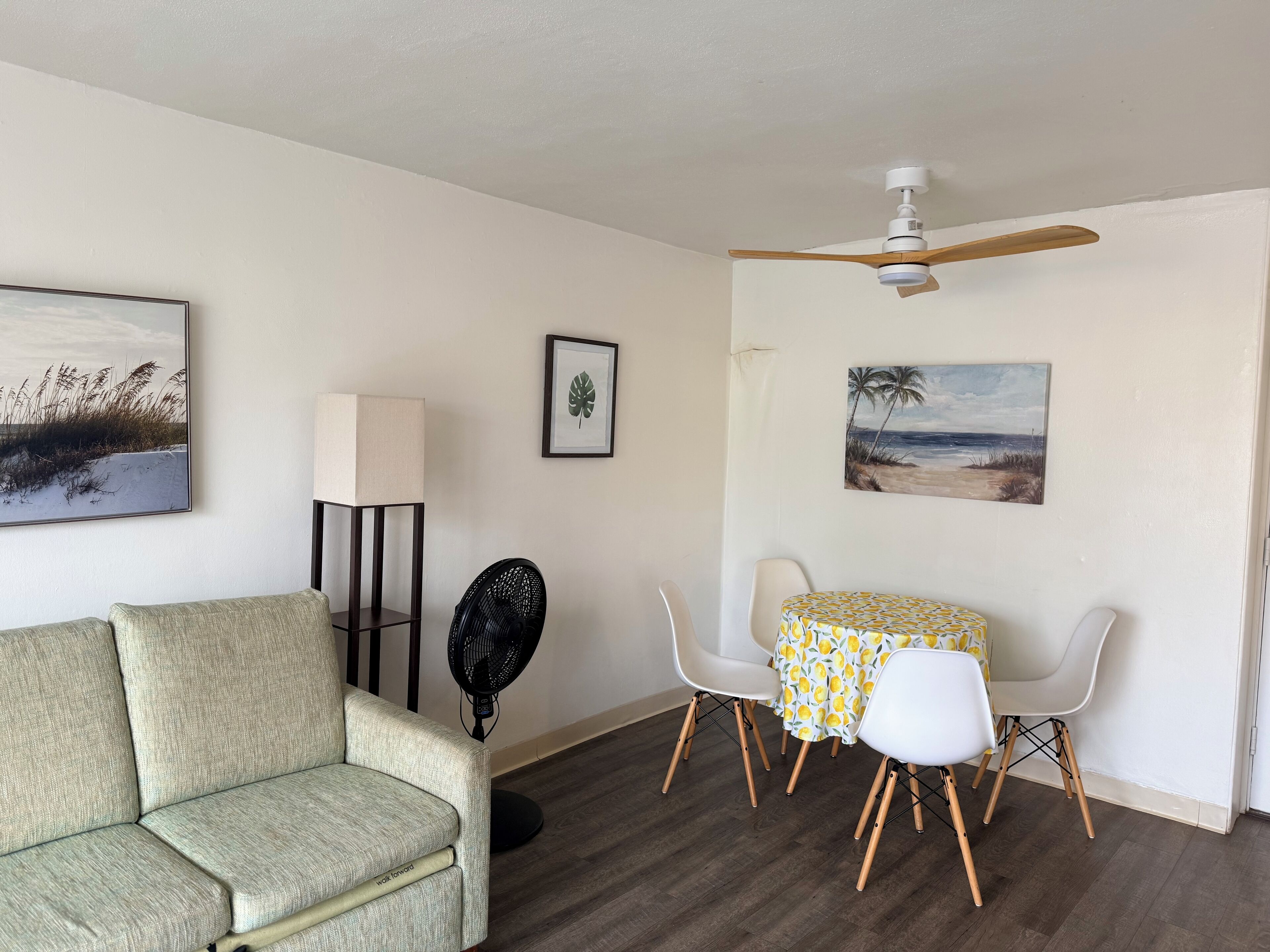 Une pièce comprenant un canapé, un ventilateur, une table avec des chaises et des ventilateurs de plafond.