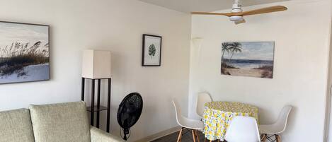 Une pièce comprenant un canapé, un ventilateur, une table avec des chaises et des ventilateurs de plafond.