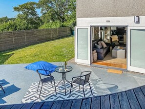 Eine Terrasse im Freien mit Tisch, Stühlen und einem blauen Kissen.