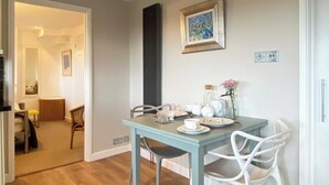 En matplats med ett ljusblått bord, vita stolar och en inramad tavla på väggen.