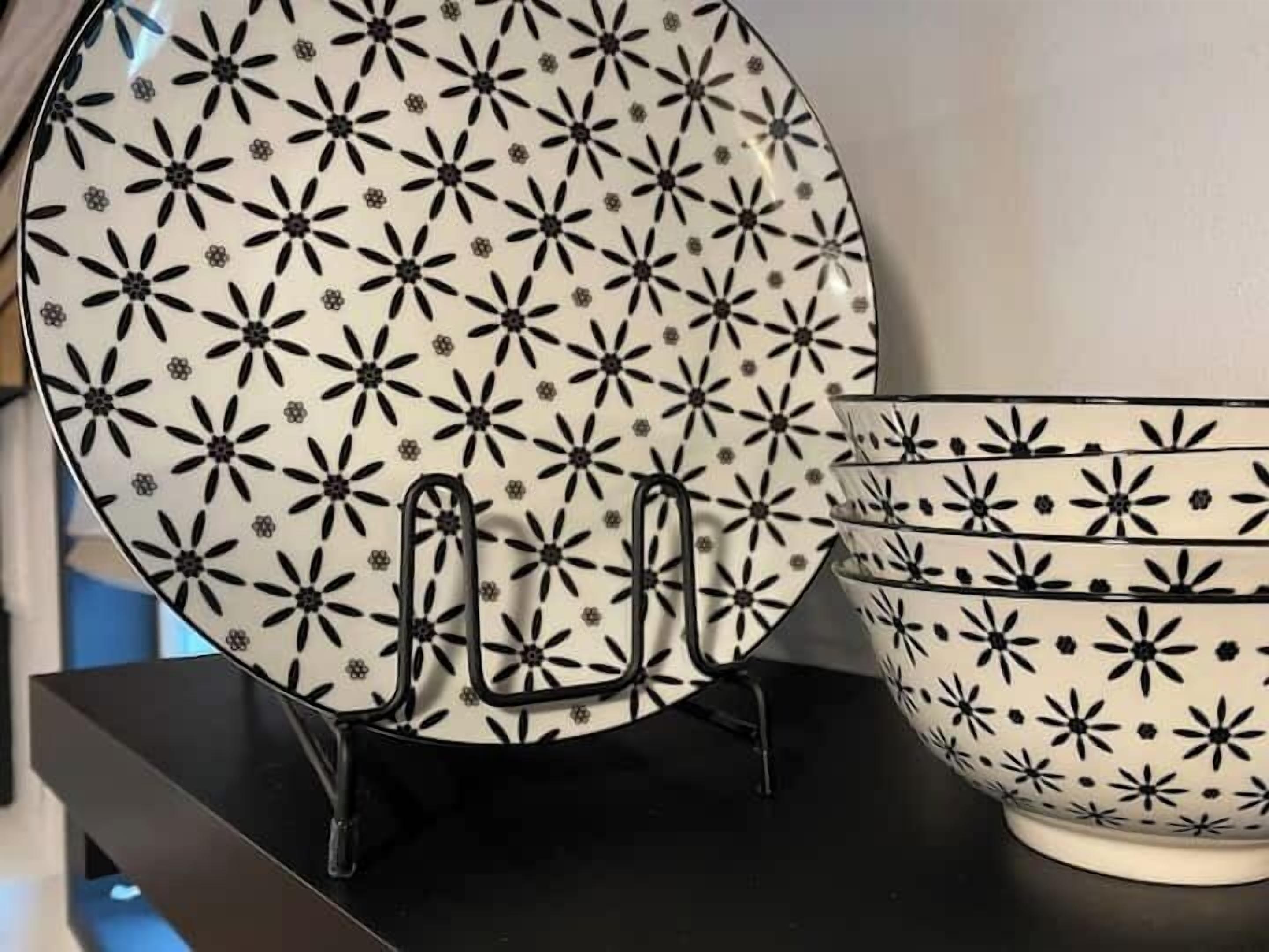 Un ensemble d’assiettes blanches ornées de motifs floraux noirs, un saladier noir et un présentoir noir.