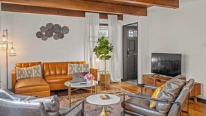 A modern living room with a brown leather sofa, a grey sofa, a coffee table, and a TV. - Designer Home in Walkable Historic Greendale (Greendale)