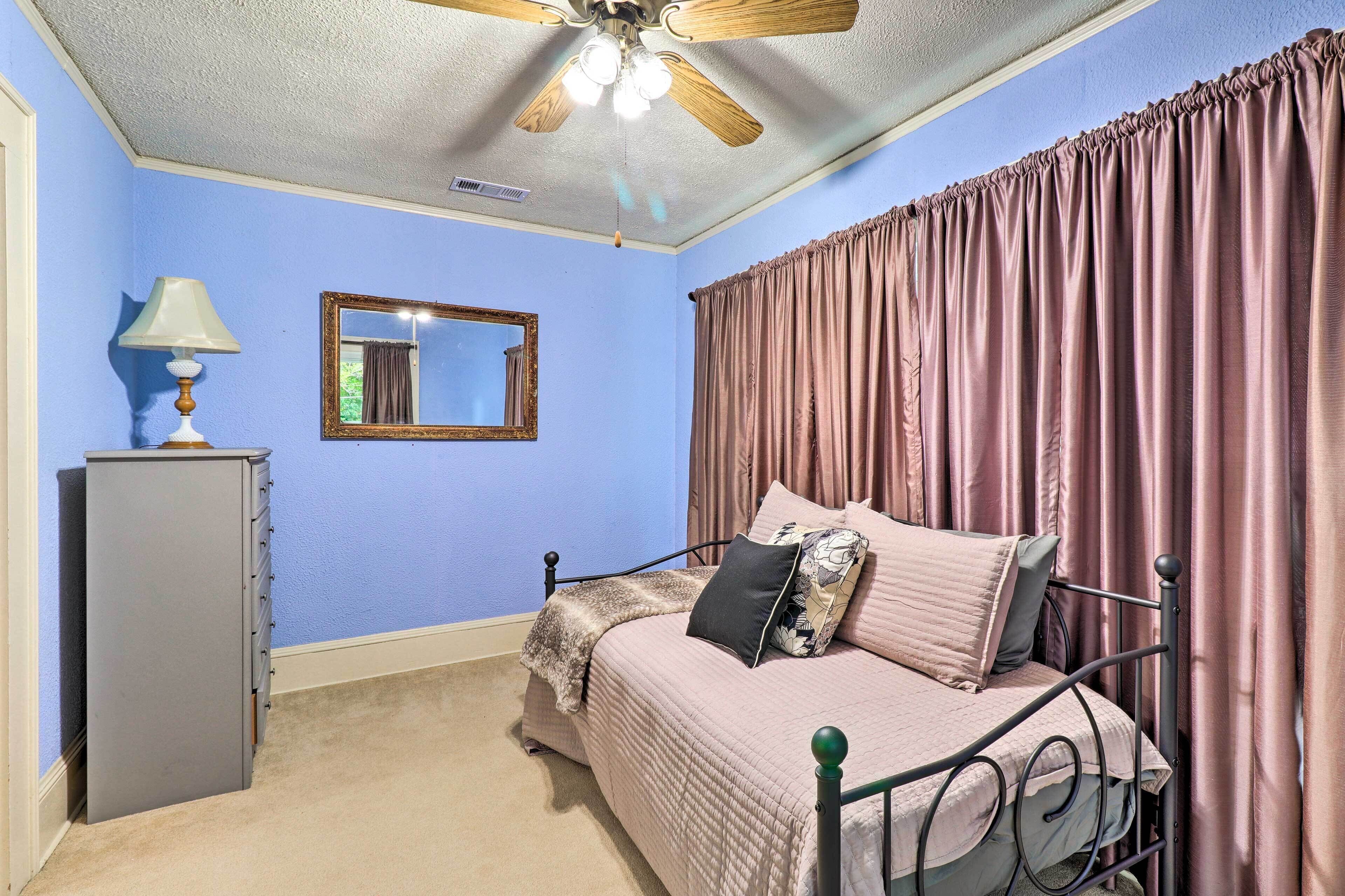 A bedroom with a bed, a ceiling fan, a dresser, and a mirror.