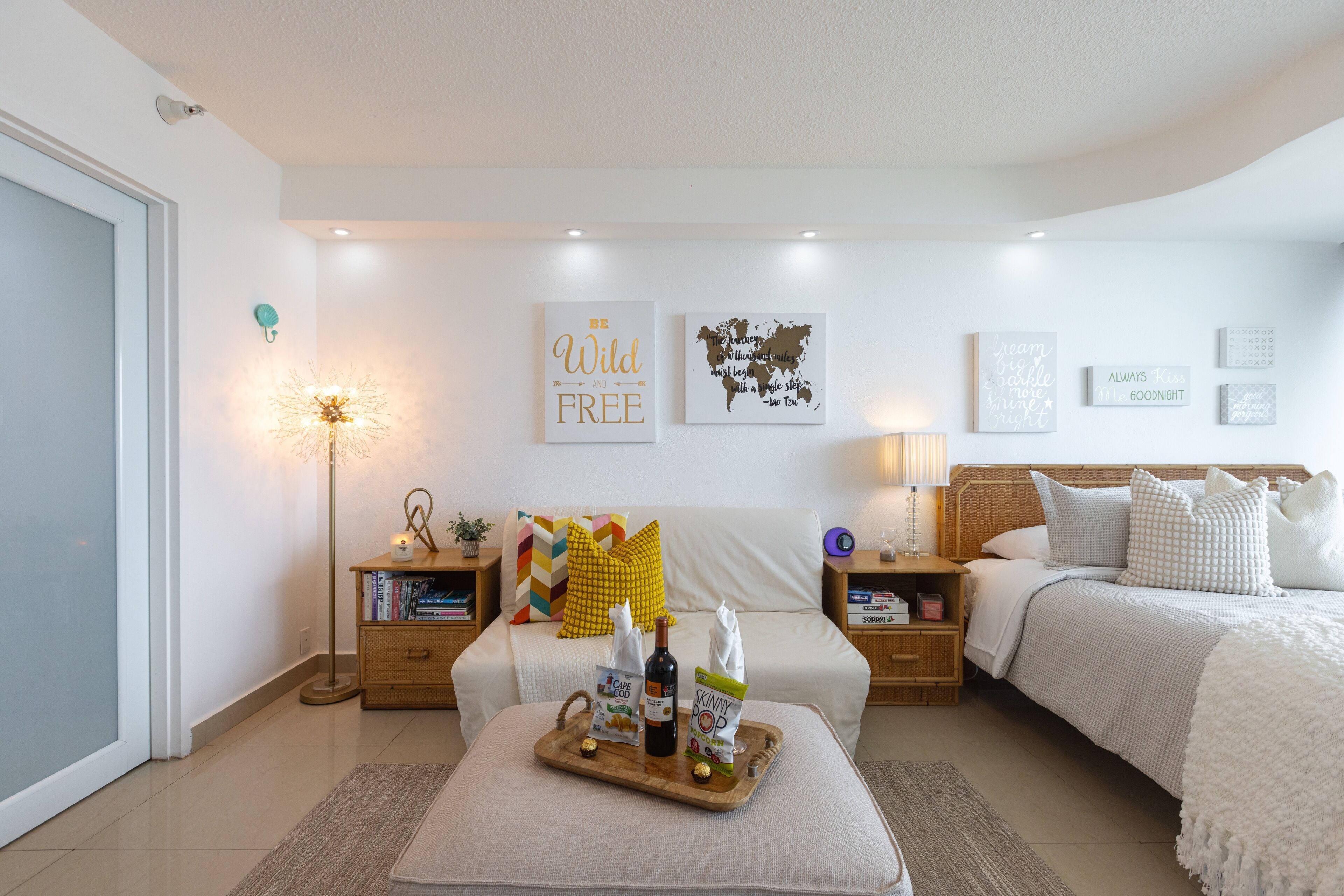 A well-lit bedroom with a bed, bedside tables, a bedside lamp, and wall art.