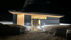 A modern building with a large entrance and a visible chimney emitting smoke.