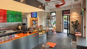 Un café moderno con una barra que exhibe diferentes productos alimenticios y una pizarra con bebidas y opciones de desayuno.
