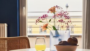 Una mesa redonda con un vaso de bebida amarilla, un bol de pan y una jarrón con flores.