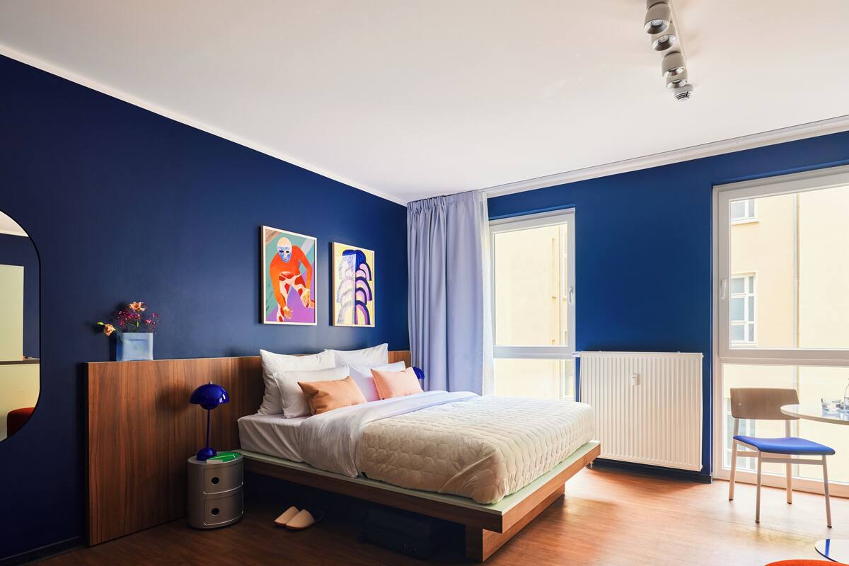 A modern bedroom with a bed, a bedside table, a chair, and a window.