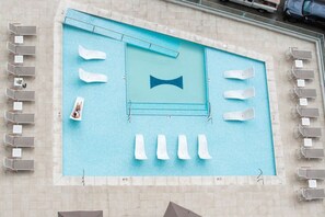 A rooftop pool with multiple sun loungers and a diving board.
