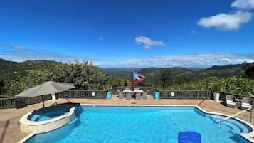 Relax by the pool with a scenic view of rolling hills and greenery.