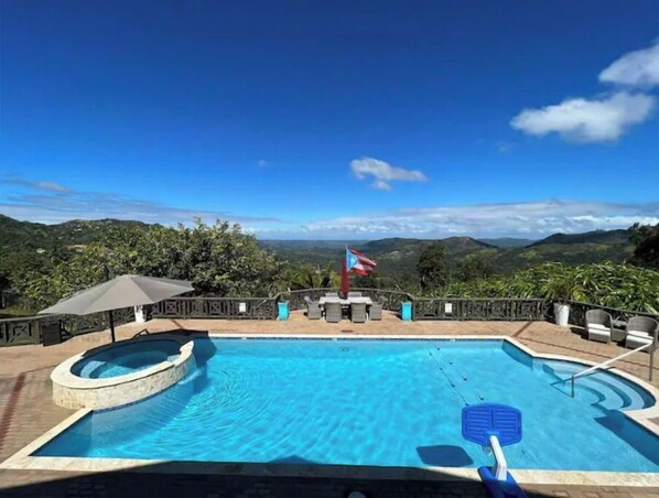 Relax by the pool with a scenic view of rolling hills and greenery.