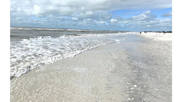 A beach with waves gently lapping onto the shore, a clear sky, and a few people in the distance. -  Waterfront House | Private Heated Pool &. Jacuzzi| 1 mile to beach| 5 Beds (Marco Island)