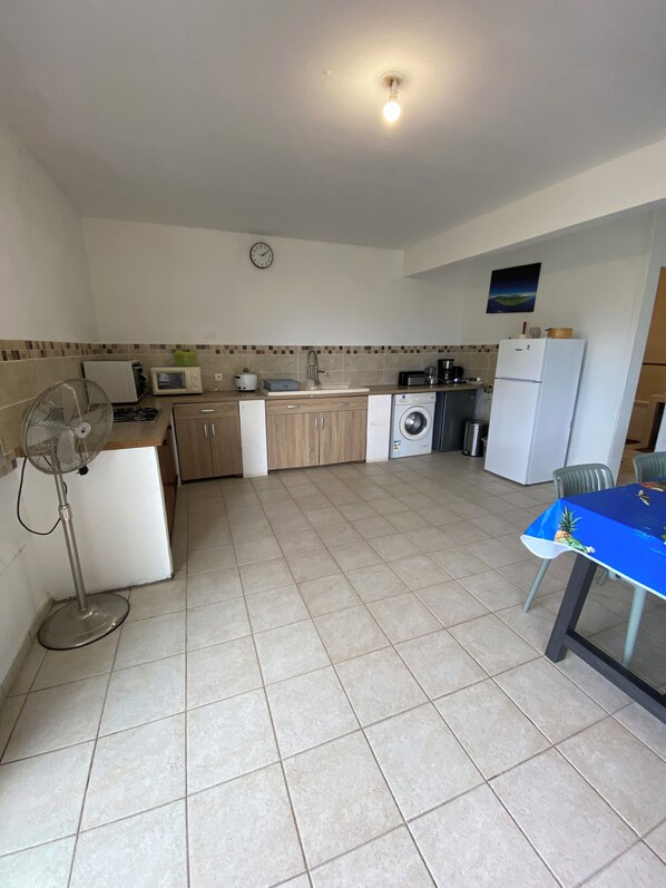 A compact kitchen with a microwave, sink, and a clock on the wall.