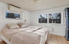 A bedroom with a bed, two windows, a lamp, and a radiator.