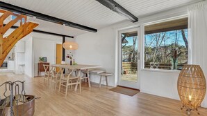 Una cocina moderna con armarios blancos, una mesa de comedor de madera y un amplio ventanal con vistas al exterior.
