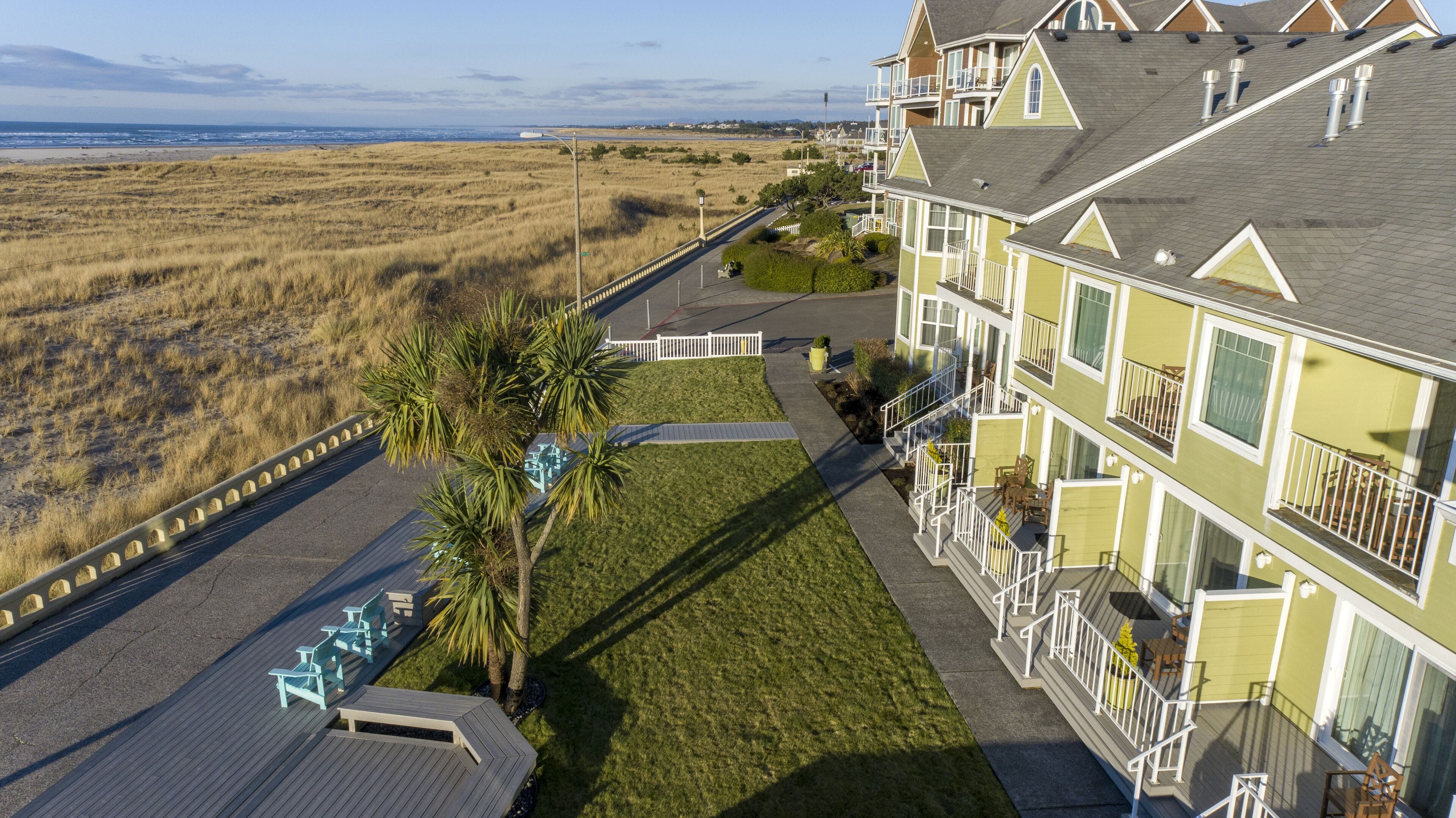 A beachfront hotel with a patio area, outdoor seating, and a view of the beach.