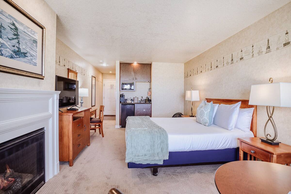 A hotel room with a bed, desk, chair, and a fireplace.