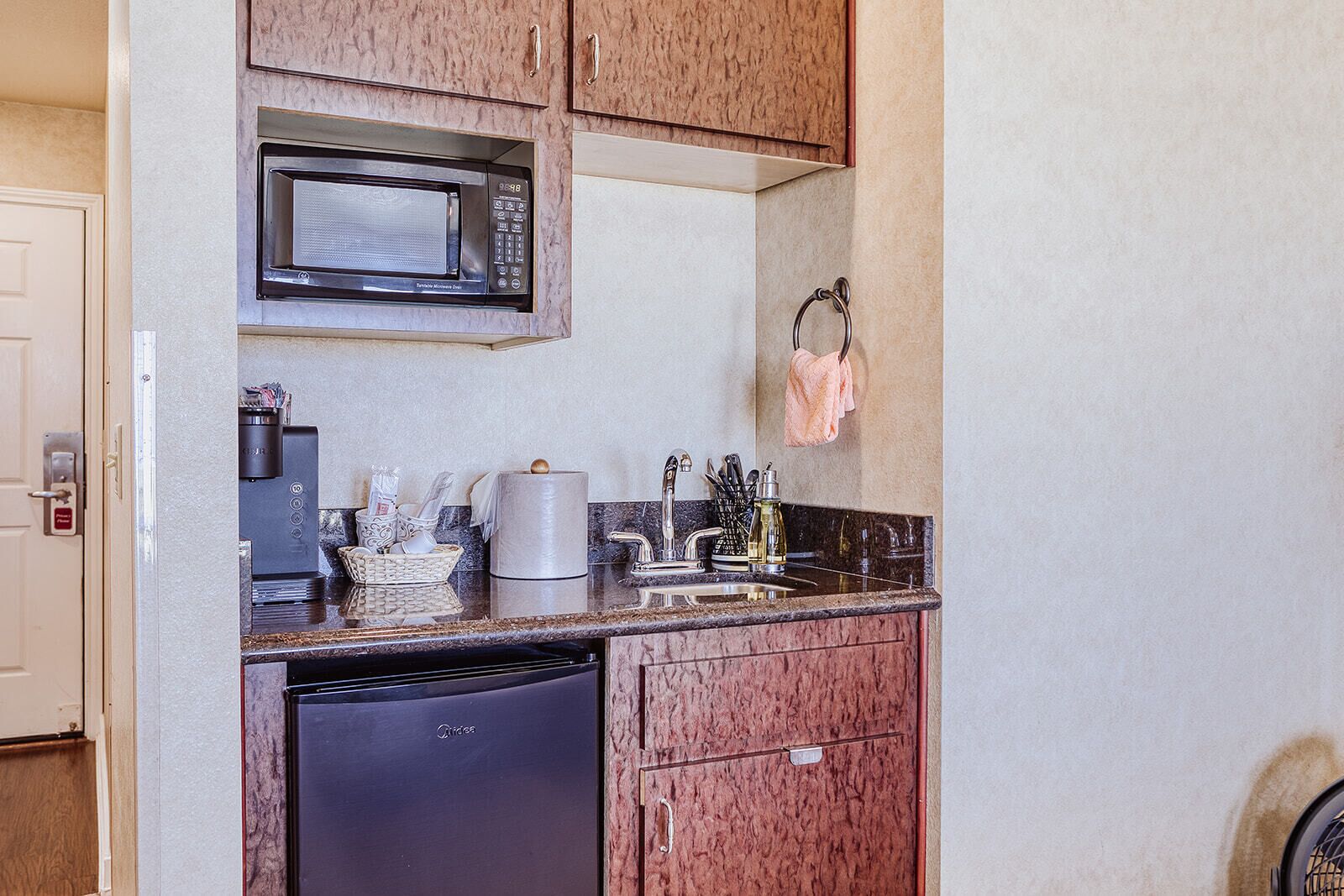 Una cocina compacta con microondas, cafetera y lavavajillas integrados.