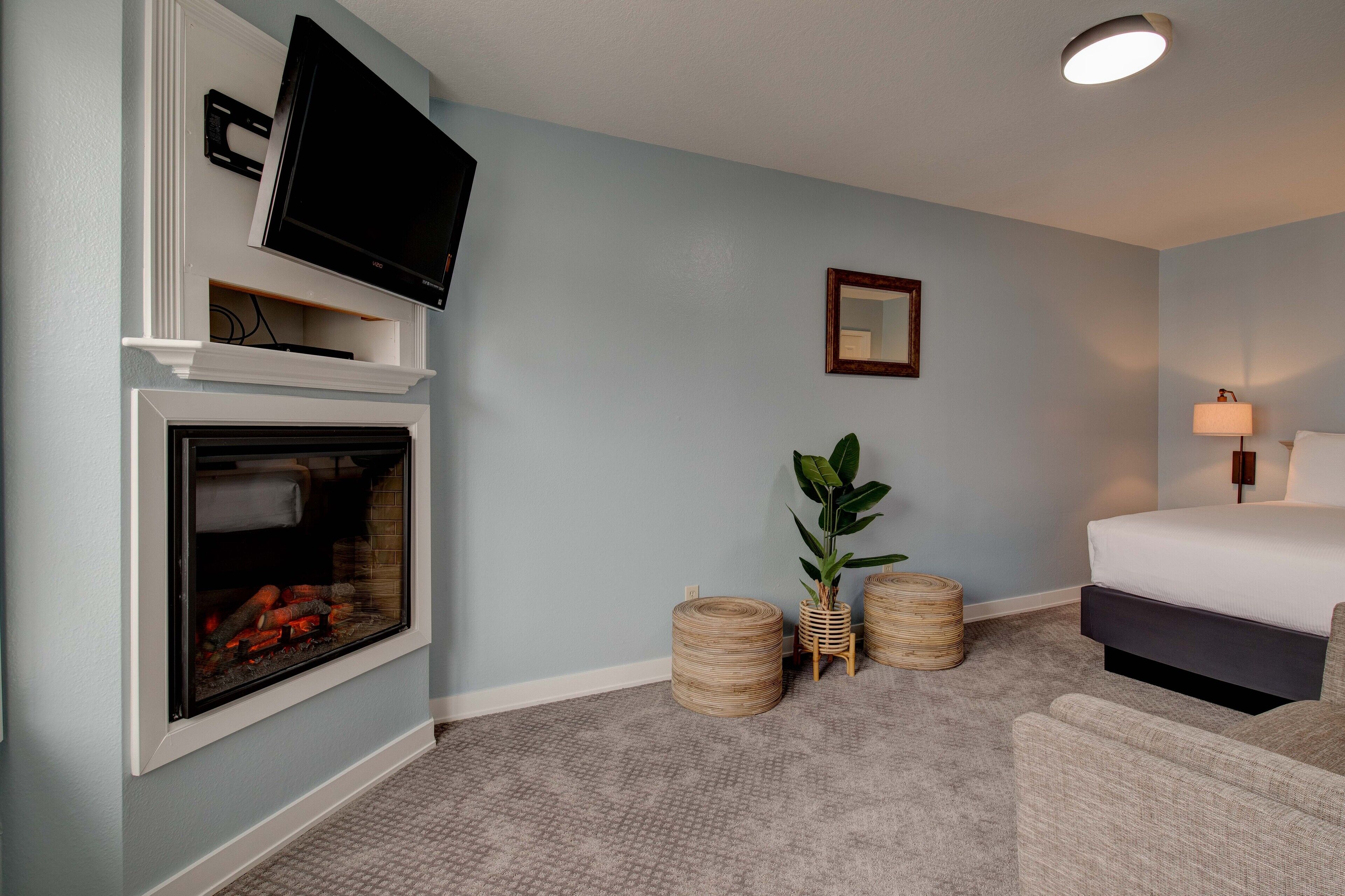 A hotel room with a fireplace, a bed, a television, and a bedside lamp.