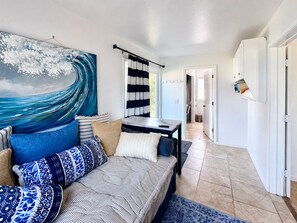 Een moderne woonkamer met een bank, een eettafel en een groot abstract schilderij.