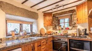 A kitchen with wooden cabinets, a stone wall, a window, and various kitchen appliances.