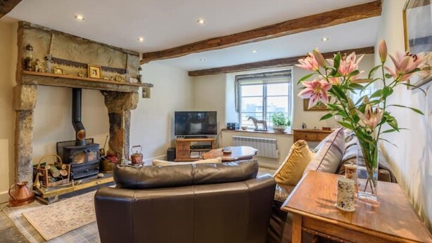 A cozy living room with a stone fireplace, a television, and comfortable seating.