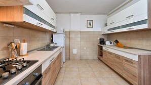 A modern kitchen with a gas stove, white cabinets, and a microwave. - Pet friendly home in Turnisce (Turnisce)