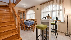 A dining area with a wooden staircase, a dining table set for four, and a clock on the wall. - Pet friendly home in Turnisce (Turnisce)