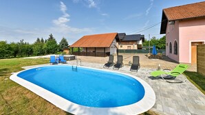 A swimming pool with lounge chairs, a covered patio, and a house with a tiled roof. - Pet friendly home in Turnisce (Turnisce)