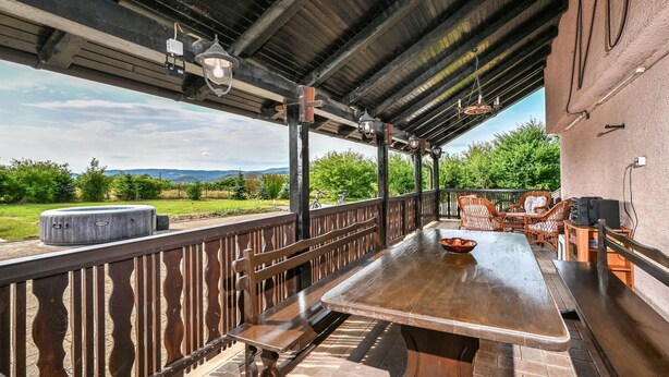 An outdoor patio with a wooden table and chairs, a hot tub, and a view of the countryside. - Pet friendly home in Turnisce (Turnisce)
