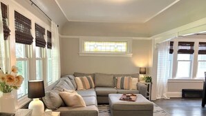 A living room with a sectional sofa, a small ottoman, and a patterned rug. - Sunny 3BR Craftsman Bungalow | Bay View (Milwaukee)