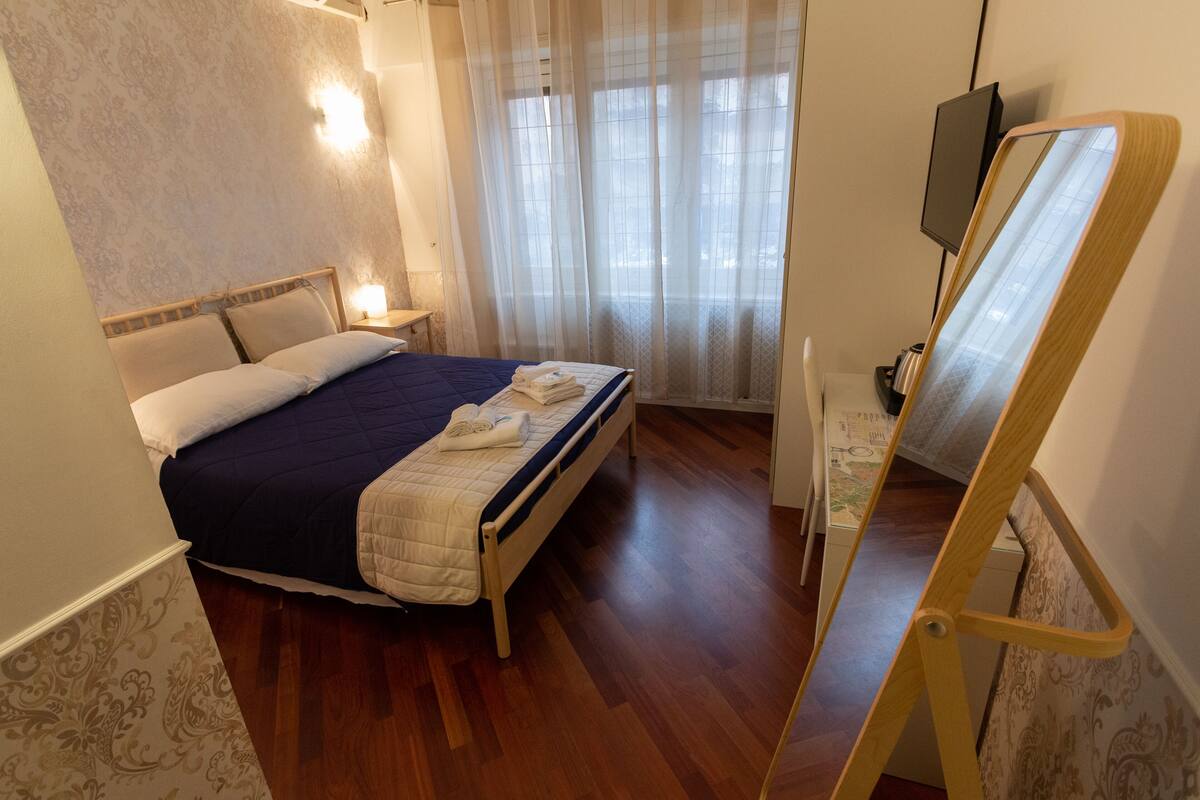 Ein Schlafzimmer mit Bett, Nachttischen, einem Fernseher und Holzboden.