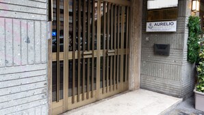 A hotel entrance with a metal gate, a sign for 'Aurelio Deluxe Rooms', and a potted plant on the right. - Aurelio Deluxe Rooms (Rome)